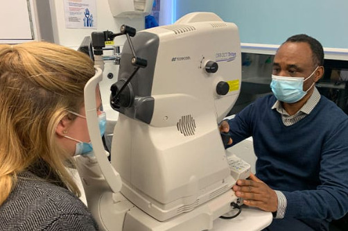 Optician studies the eyes of a patient