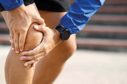 A person holding their knee in pain - how to know if you need a knee replacement blog