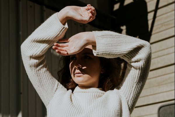 Woman holding her hands up against the sun