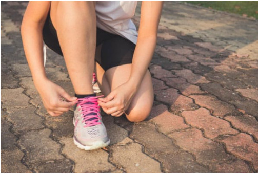 Runner kneels to ties up her laces before exercising