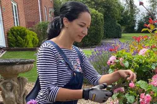 woman prunes some flowers in a garden after a hip replacement