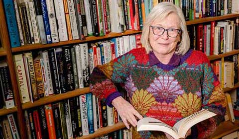 Shepton cataract surgery patient, Valerie Stewart, next to a wall of books