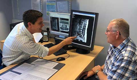 Wyn Griffiths with his consultant looking at a scan about his spinal surgery