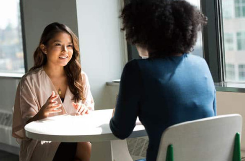 Two women talk over a table during a job interview