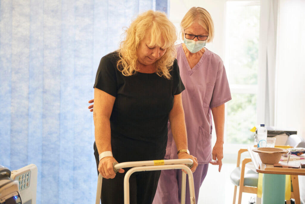 Clinician helping patient walk with crutches with knee and hip pain