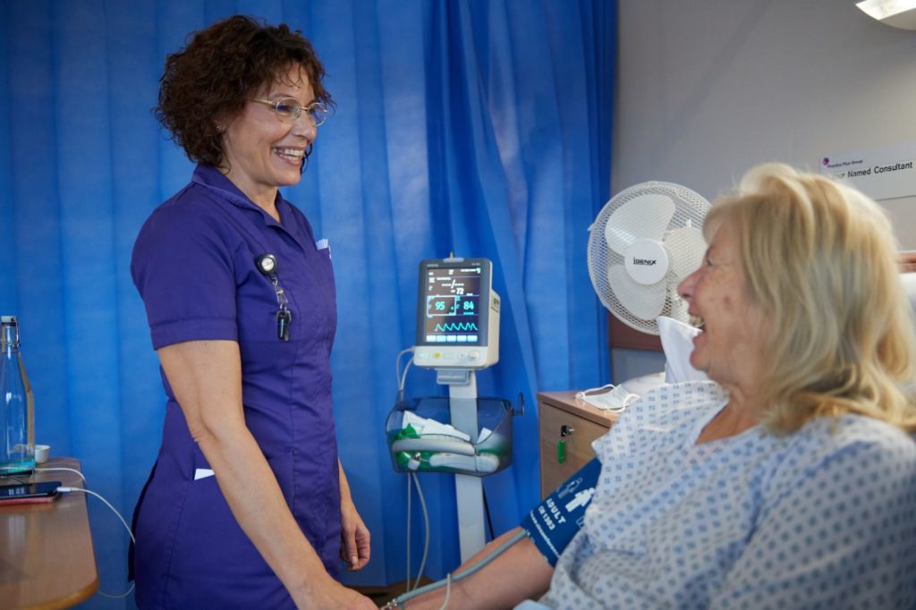 Apprentice nurse and female patient laugh together in Shepton Mallet hospital