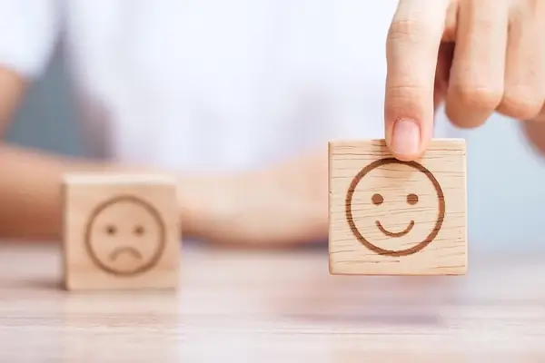 Two wooden squares carved with happy and sad faces