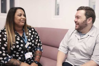Two of our colleagues smiling sat on a sofa discussing jobs and working in Health in Justice