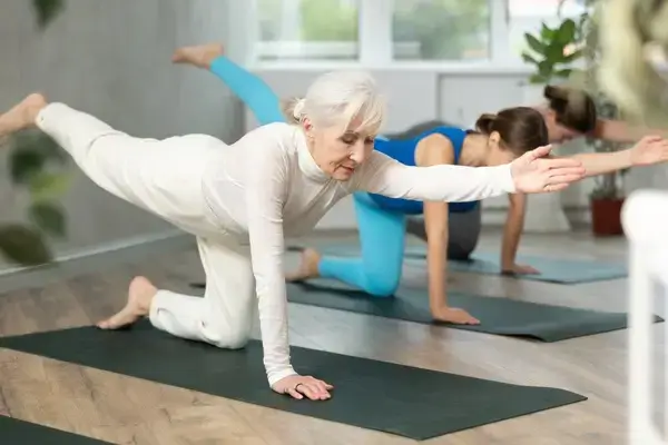 Older woman practicing yoga on a mat after knee surgery