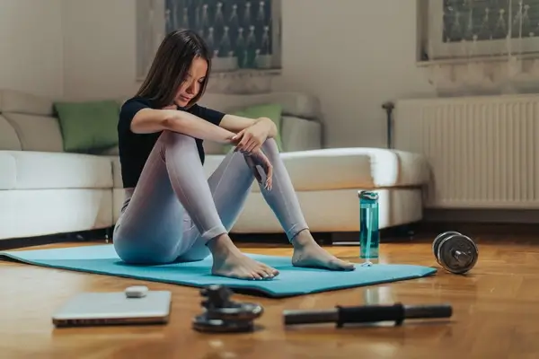 A woman sitting on a yoga mat experiencing hernia pain