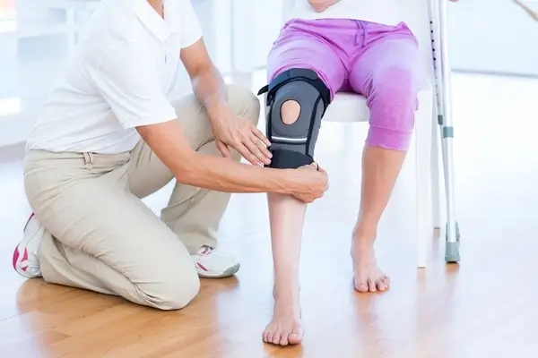 Patient with knee brace being fitted after a knee replacement 