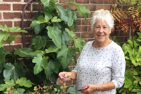 Karen, our patient from barlborough, smiling outside doing gardening after having successful knee surgery