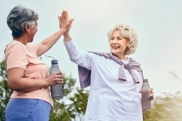 Two older women holding water bottles high-five