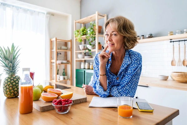 Older woman stands at a kitchen counter covered in fruit