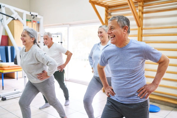 Group of older adults do hip exercises in a gym after hip replacement surgery in London