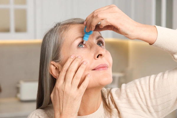 A woman putting in eyedrops after cataract surgery in Birmingham