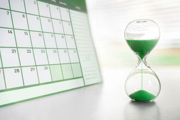 A sand filled timer next to a calendar