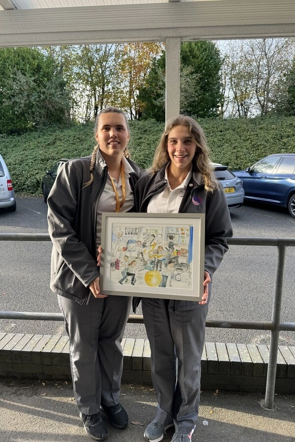 Two women holding an art work