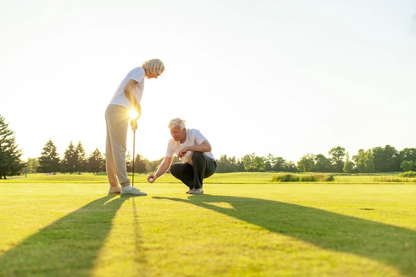 An older couple playing golf after a knee replacement on a sunny day